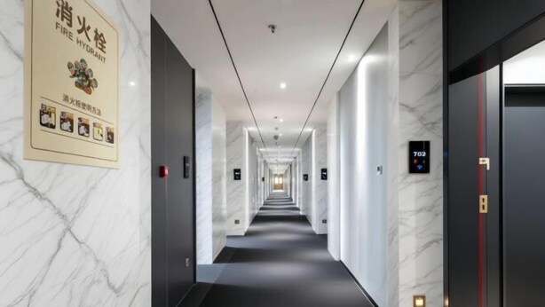 A hotel corridor with marble walls, black carpet, and a fire hydrant sign on the left. - Qinhuangdao Haishanghai International Hotel (Qinhuangdao)