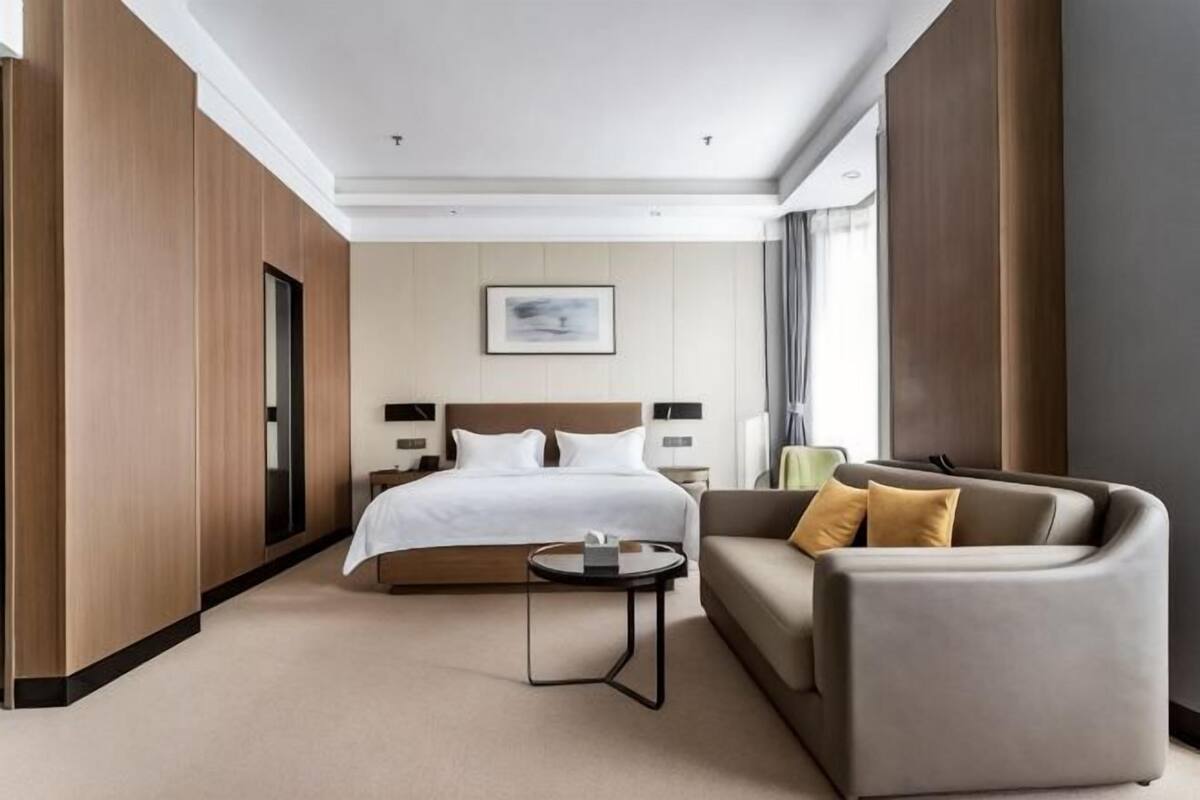 Ein Hotelzimmer mit Bett, Sofa, kleinem Tisch und Fenster.
