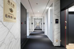 Un pasillo de hotel con paredes de mármol, alfombra negra y un cartel de seguridad contra incendios.