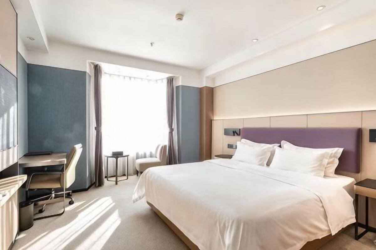 Ein Hotelzimmer mit Bett, Schreibtisch, Stuhl und Blick ins Freie.