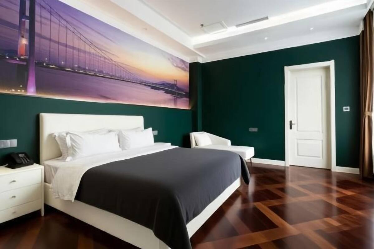 Ein Hotelzimmer mit einem großen Bett, einem Nachttisch, einem Sessel und einer Tür.