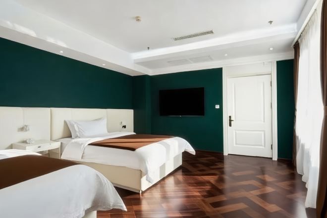 Une chambre d’hôtel avec deux lits, un téléviseur à écran plat et un plancher en parquet.