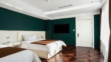 Une chambre d’hôtel avec deux lits, un téléviseur à écran plat et un plancher en parquet.
