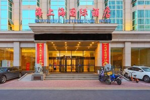 A hotel entrance with a large sign, a statue, and a few parked vehicles. - Qinhuangdao Haishanghai International Hotel (Qinhuangdao)