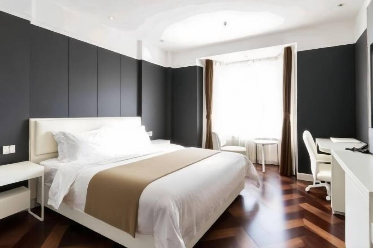 Ein modernes Hotelzimmer mit Bett, Schreibtisch, Stuhl und einem kleinen Tisch.