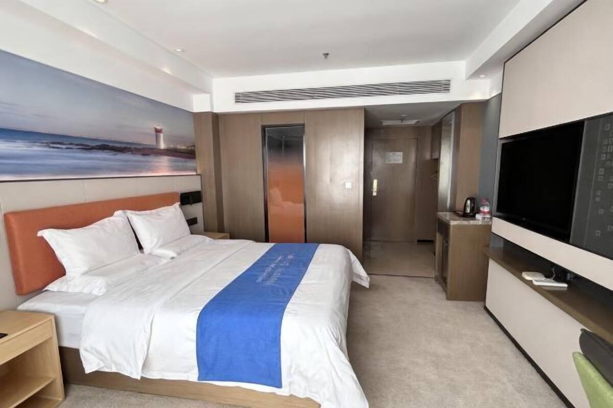 Ein Hotelzimmer mit einem Bett, einem Fernseher, einem Schreibtisch und einem Bild an der Wand.