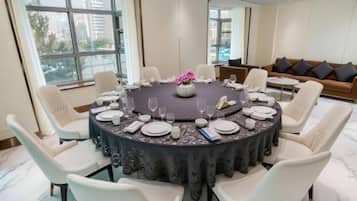 Mesa redonda para seis personas, con sillas blancas, un centro de mesa floral y mantel oscuro.