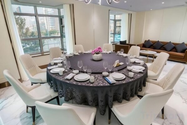 A round dining table set for six with white chairs, a floral centerpiece, and a dark tablecloth. - Qinhuangdao Haishanghai International Hotel (Qinhuangdao)