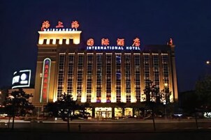Un edificio grande e iluminado con el letrero “International Hotel” bien visible.
