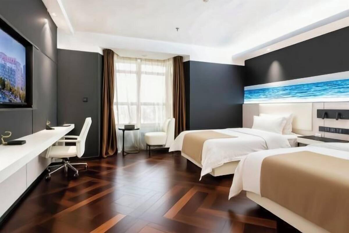 Ein Hotelzimmer mit zwei Betten, einem Schreibtisch, einem Stuhl und einem Fernseher.