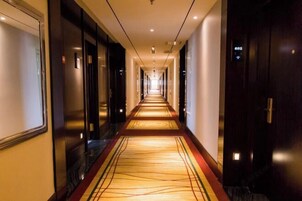 Un pasillo de hotel con piso alfombrado, puertas a ambos lados y un cartel con el número del ascensor.