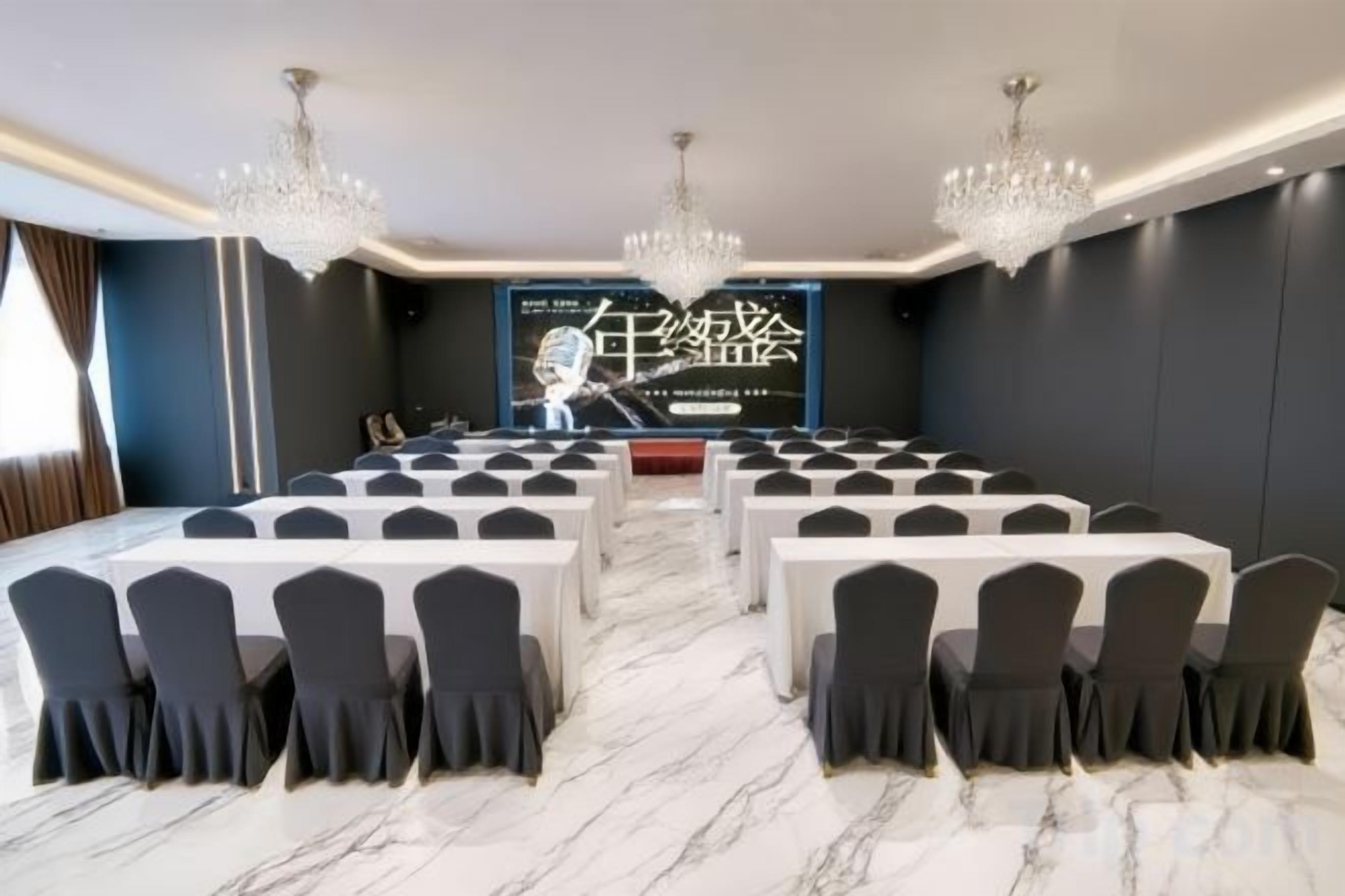 A conference room with a long table, chairs, and a large screen.