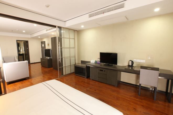 Una habitación de hotel moderna con cama, escritorio con televisor y zona de estar.