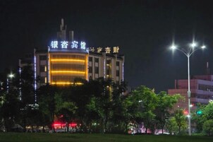 Un edificio con letreros iluminados, rodeado de árboles y farolas.