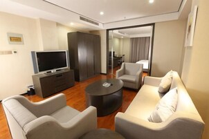 Una habitación de hotel moderna con un conjunto de sofá, un televisor de pantalla plana, una mesita de centro y un armario.