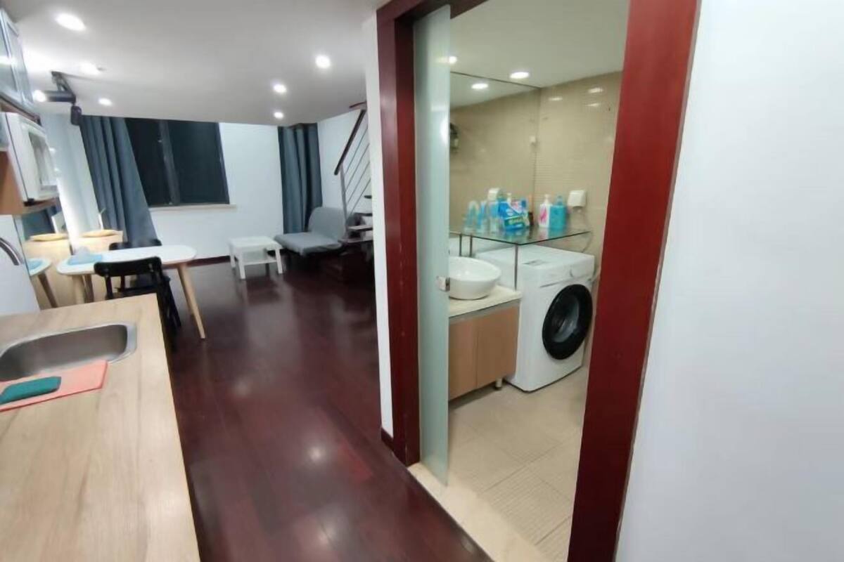Una cocina moderna con un lavamanos, una zona de comedor con mesa y sillas, y una lavadora a la vista.