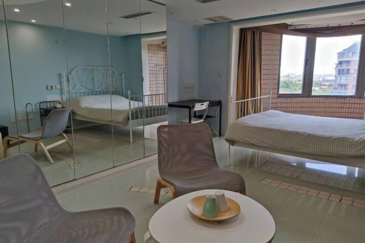 Habitación de hotel con cama, escritorio, silla y mesa redonda con taza y platillo.