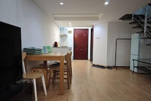 A dining area with a wooden table and chairs, a TV, and a kitchen in the background. - iNestin Shanghai (Hongfeng Road) (Shanghai)