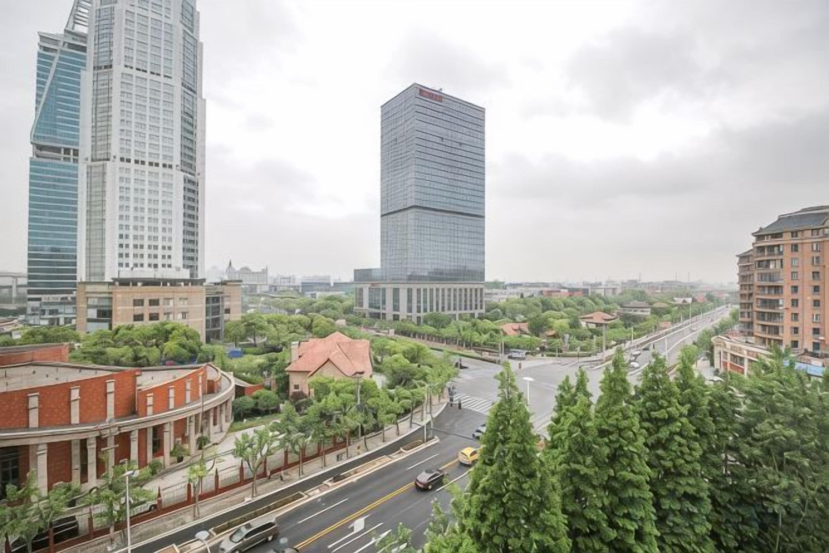 A cityscape with modern high-rise buildings, a curved road, and greenery.