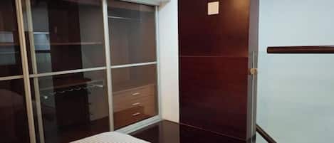 A bedroom with a bed, a wardrobe, and a sliding door.