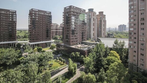 Un ensemble immobilier résidentiel composé de plusieurs immeubles à étages, entouré de verdure et bordé par une rivière.