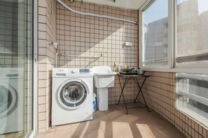 A compact laundry area with a washing machine, a small sink, and a window. - iNestin Shanghai (Hongfeng Road) (Shanghai)
