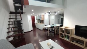 Un salon moderne avec un escalier, un coin repas et un téléviseur.