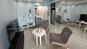Un salon moderne avec un canapé, une table basse, un téléviseur et un mur miroitant.