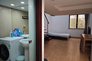 A room with a bed, a window, a table, and a washing machine. - iNestin Shanghai (Hongfeng Road) (Shanghai)