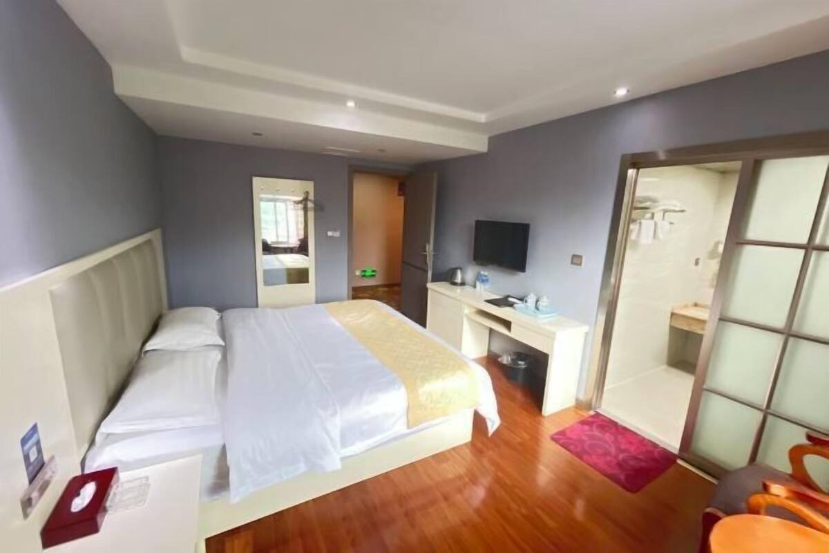 Une chambre d’hôtel équipée d’un lit, d’un bureau, d’une chaise, d’une télévision et d’une porte coulissante donnant accès à la salle de bain.