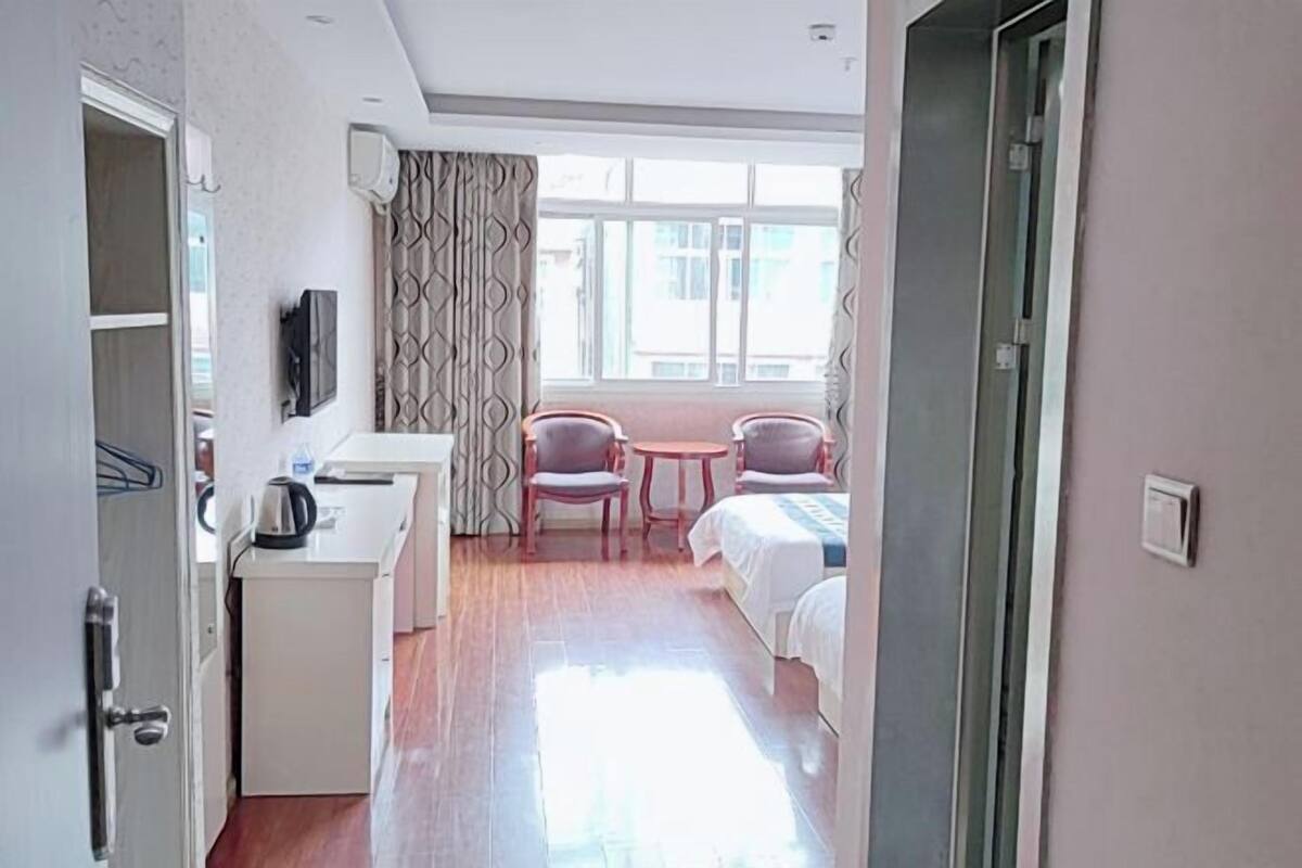 Une chambre d’hôtel comprenant un lit, un bureau, deux chaises, une petite table et un téléviseur.