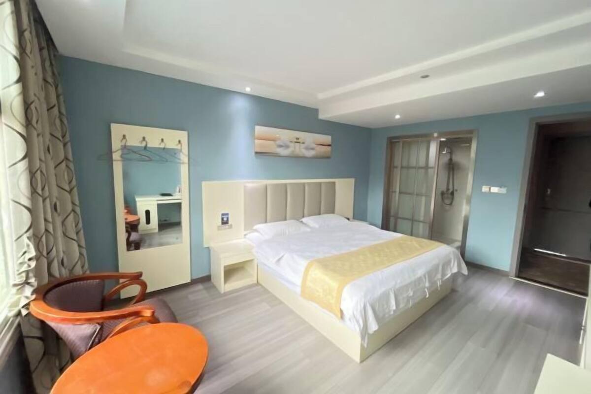 Une chambre d’hôtel comprenant un lit, une table de chevet, une chaise, un miroir et un espace douche.