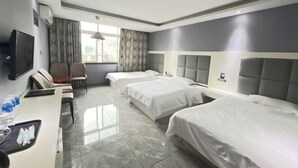 Habitación de hotel con cama, escritorio, silla, televisor y ventana con cortinas.