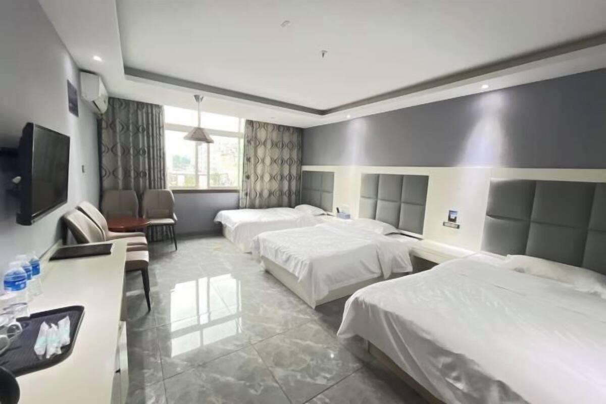 Une chambre d’hôtel avec un lit, un bureau, une chaise, une télévision et une fenêtre avec des rideaux.