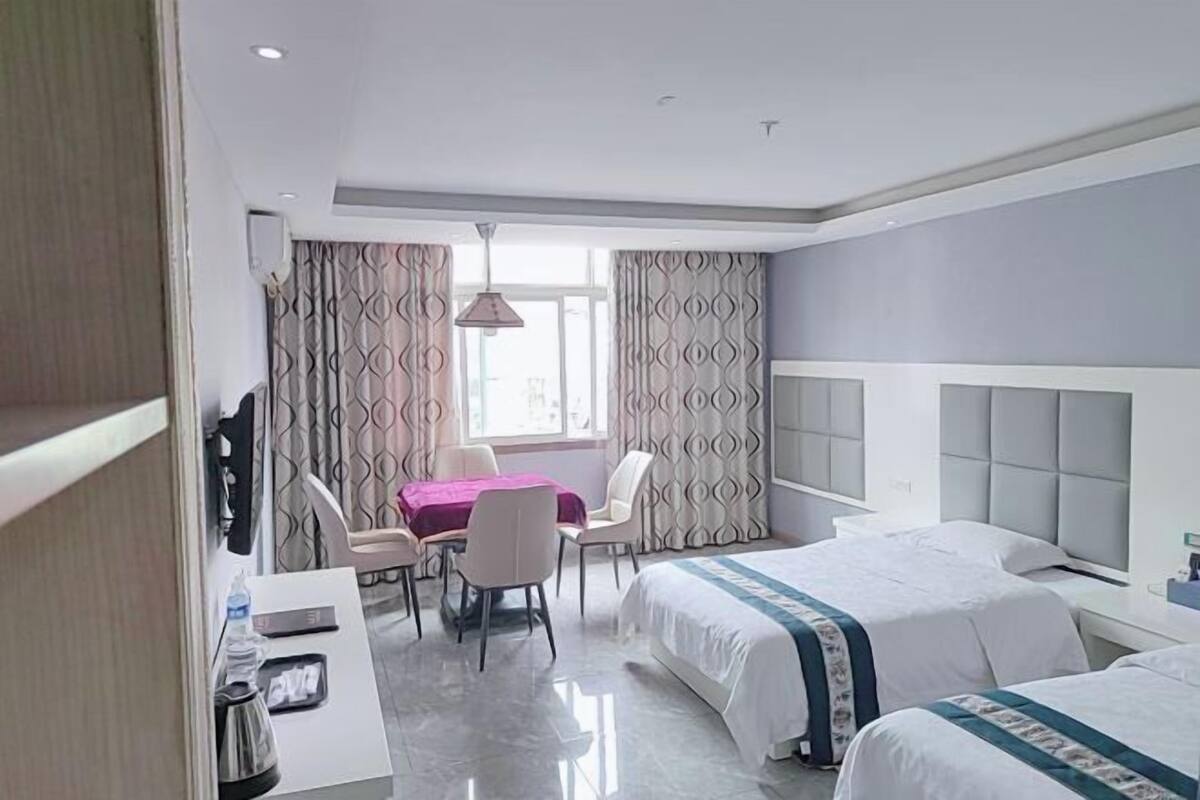 Une chambre d’hôtel avec deux lits, un bureau, une chaise, une table et des rideaux.