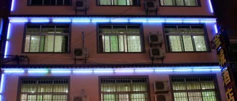 A multi-story hotel with illuminated signage and air conditioning units.