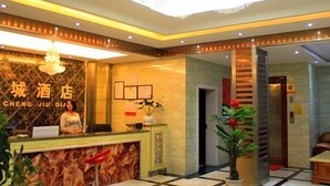 Zona de recepción de un hotel con un mostrador de mármol, un candelabro y un letrero que dice 'CHENG JIU DI'.