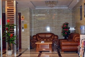 Un hall con un sofá de cuero marrón, una mesa de centro de madera y una planta en maceta.