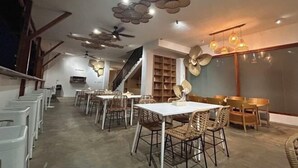 A spacious dining area with high ceilings, wicker chairs, and a central white table. - Fun Hotel (Panglao Municipality)
