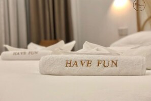 A hotel room with neatly folded towels on the bed, each with 'HAVE FUN' embroidered on them. - Fun Hotel (Panglao Municipality)