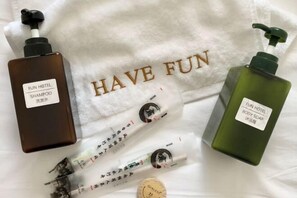 A towel with "HAVE FUN" printed on it, and two bottles of Fun Hotel body soap and shampoo. - Fun Hotel (Panglao Municipality)