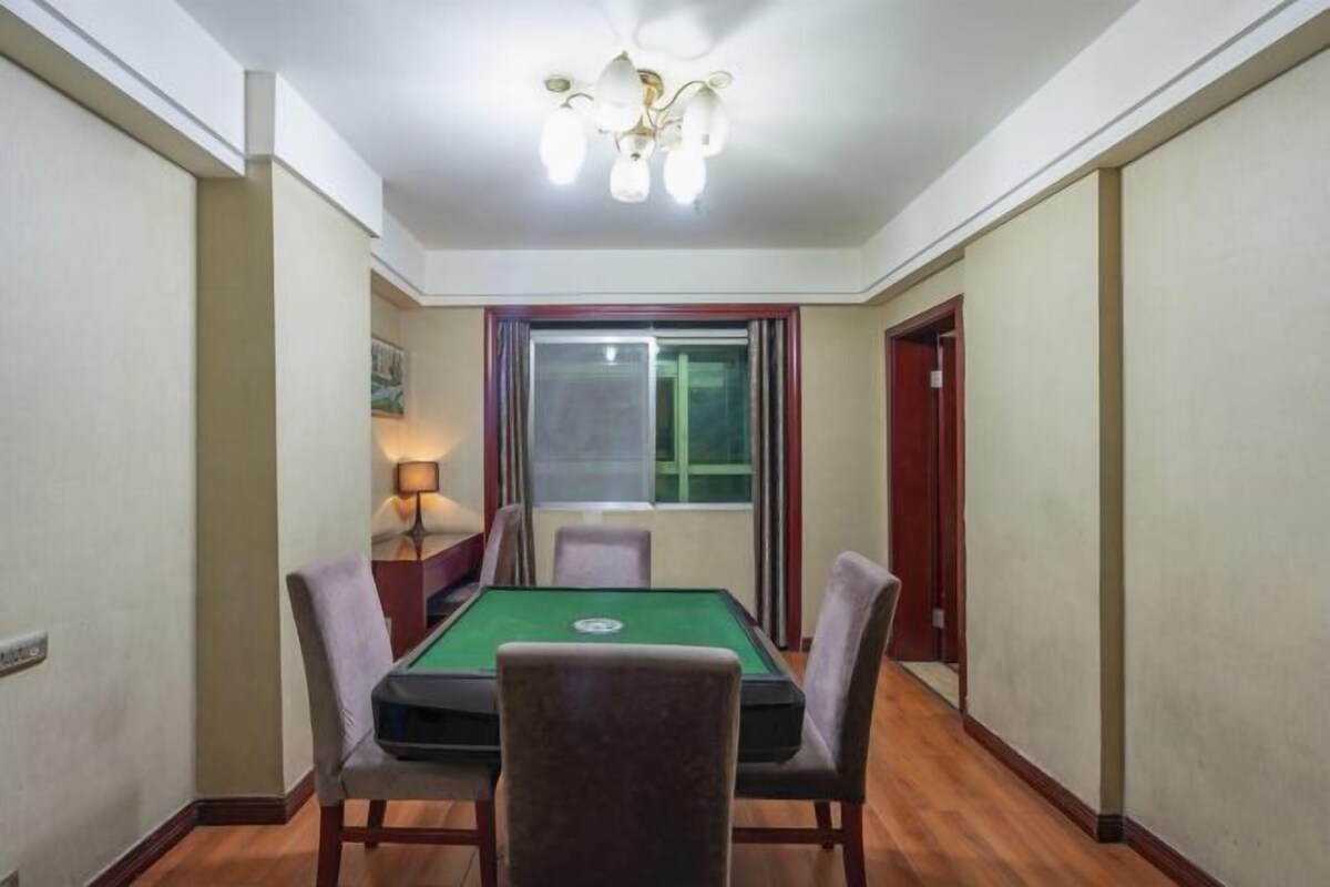 A room with a pool table, four chairs, a lamp, and a window with curtains.