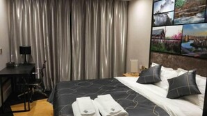 A hotel room with a bed, a desk, a chair, and a curtain. - Chonpines Hotel (Xinyu)