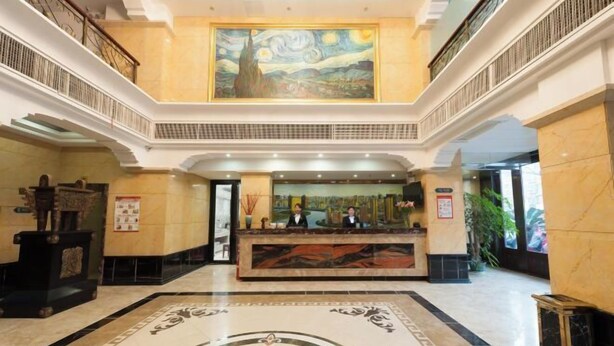 A lobby with a reception desk, a large painting above it, and a marble floor with a central design. - Chonpines Hotel (Xinyu)