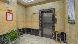 A lobby with a marble floor, a reception desk, a plant, an elevator, and a wall-mounted sign. - Chonpines Hotel (Xinyu)