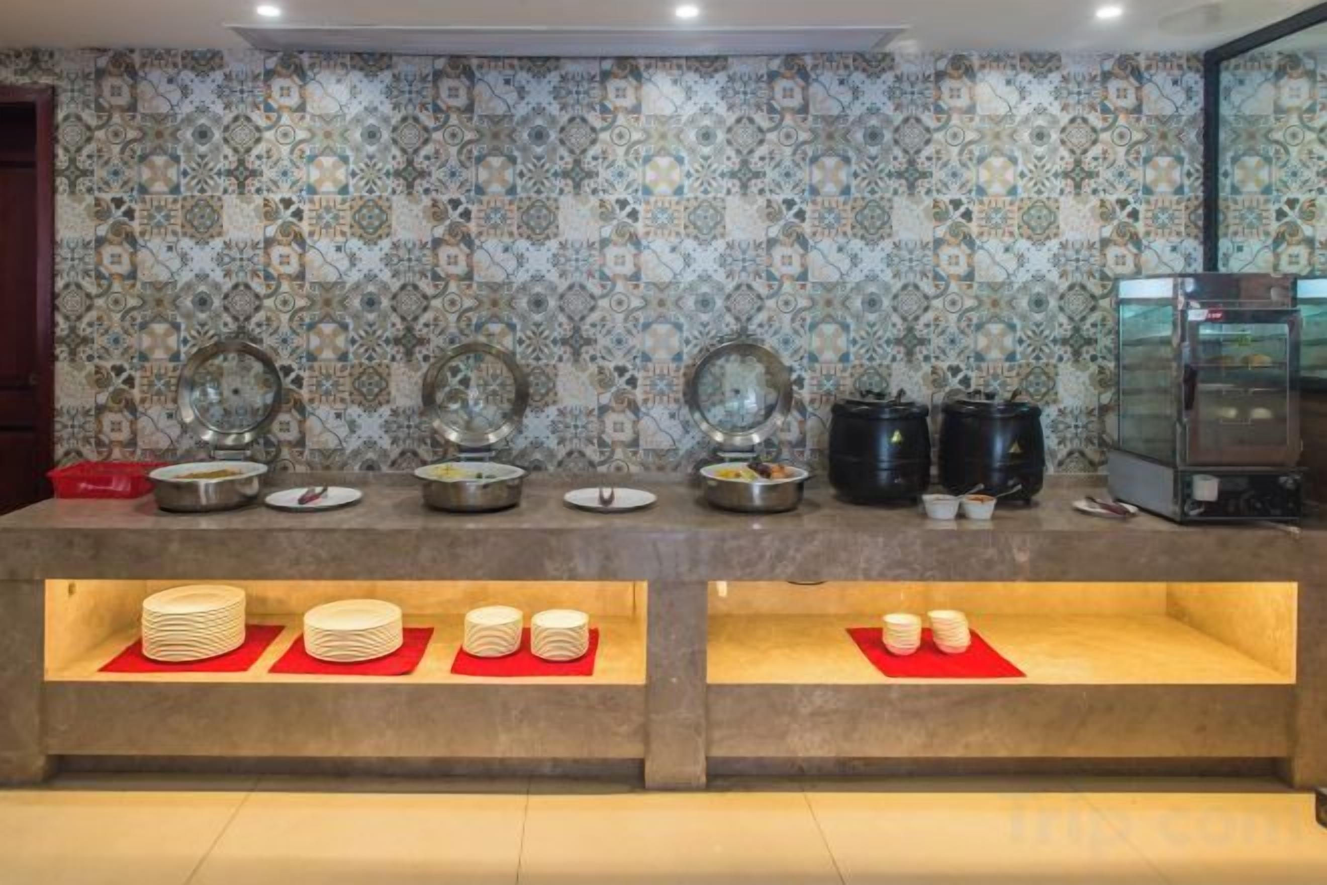A buffet setup with multiple serving stations, a coffee machine, and a tiled backsplash.