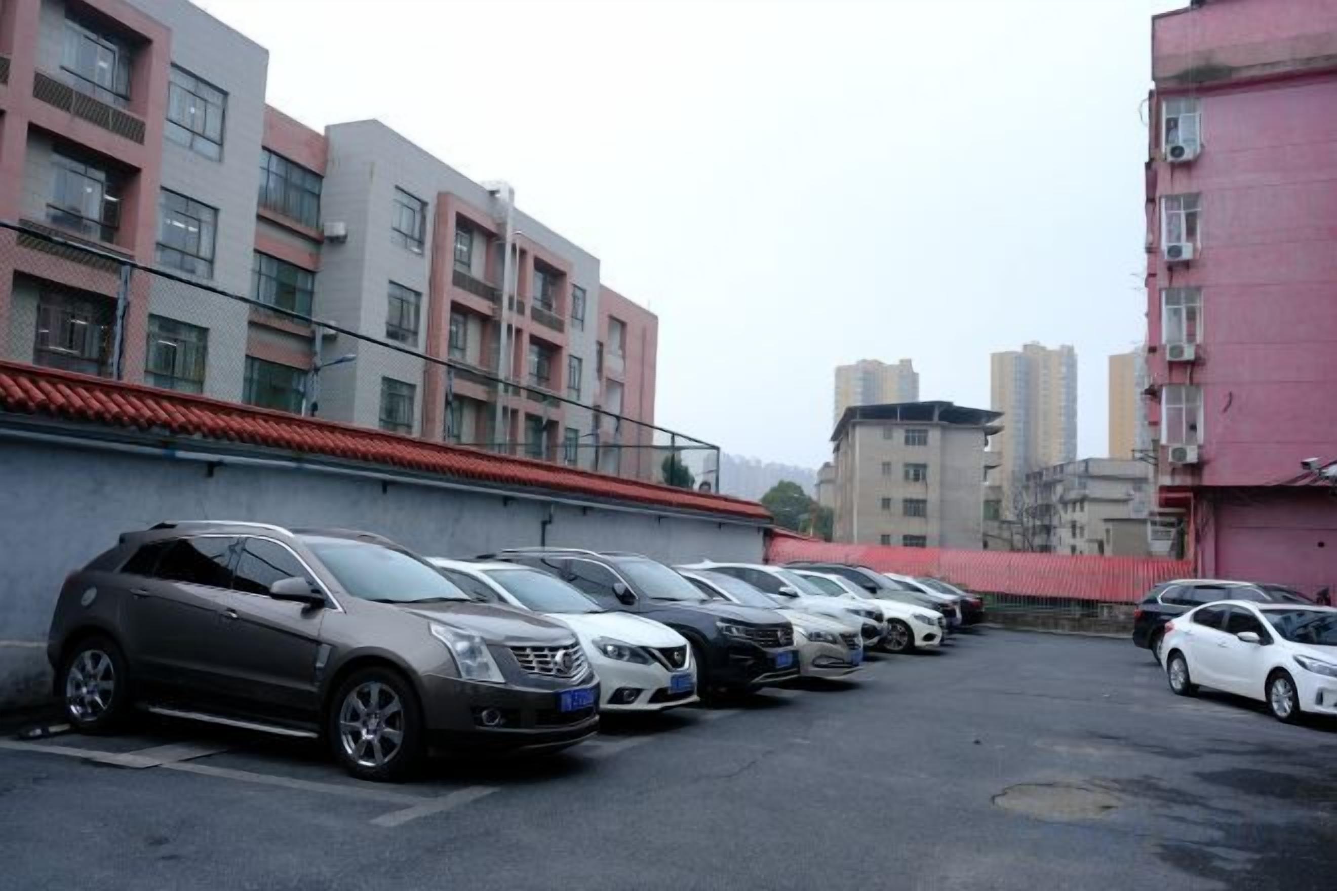 Un estacionamiento con varios automóviles estacionados frente a edificios residenciales.