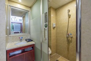 A bathroom with a glass-enclosed shower, a sink with a mirror above it, and a toilet. - Chonpines Hotel (Xinyu)