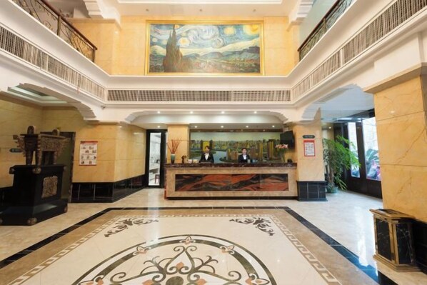 A hotel lobby with a reception desk, a large painting on the wall, and a marble floor. - Chonpines Hotel (Xinyu)
