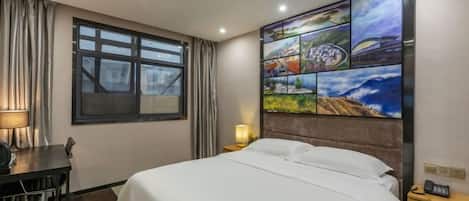 A hotel room with a bed, a desk, a chair, a lamp, a nightstand, and a wall with a cityscape painting.